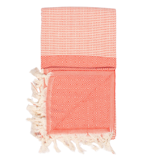 A cotton towel in a tangerine color with an intricate design and white fringe.