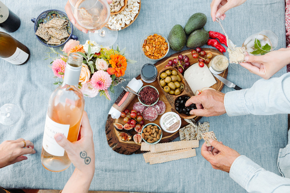 Party spread of Santa Barbara Company snacks, appetizers, wine and flowers.